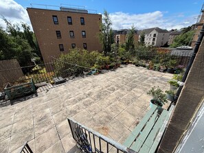Eine Dachterrasse mit gefliestem Boden, umgeben von Blumentöpfen und einem Fahrrad.