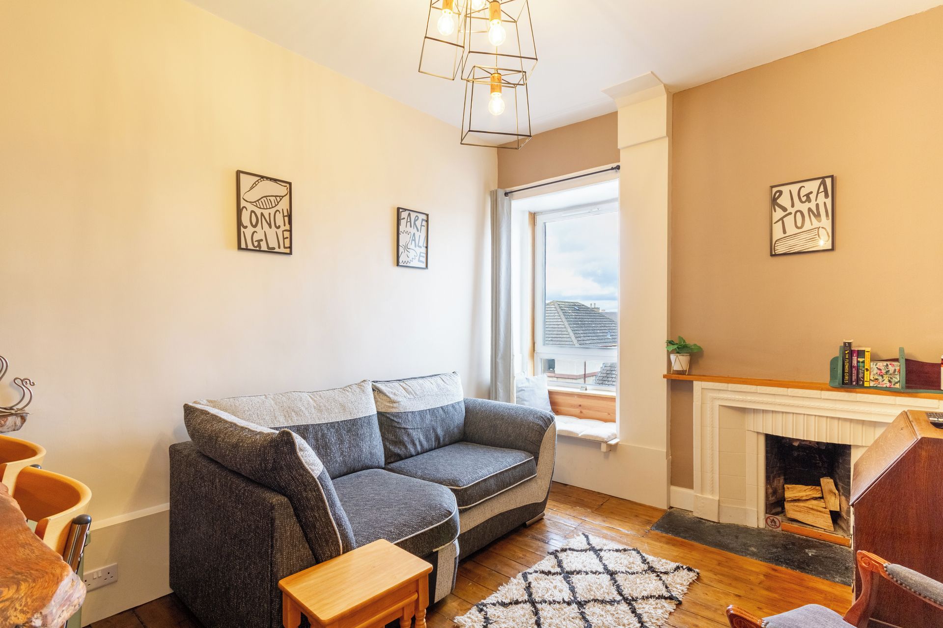 A cozy living room with a grey sofa, wooden side table, and a fireplace.