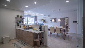 Uma cozinha moderna com uma ilha central, área de jantar com cadeiras e uma janela grande.
