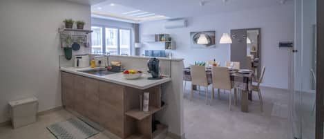 A modern kitchen with a central island, dining area with chairs, and a large window.