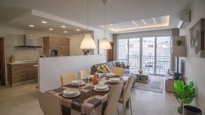 Um apartamento moderno com área de jantar, cozinha e varanda.
