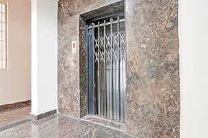 Pared de mármol con puerta de ascensor metálica.