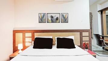 Habitación de hotel con cama, mesita de noche, lámpara, silla y aire acondicionado de pared.