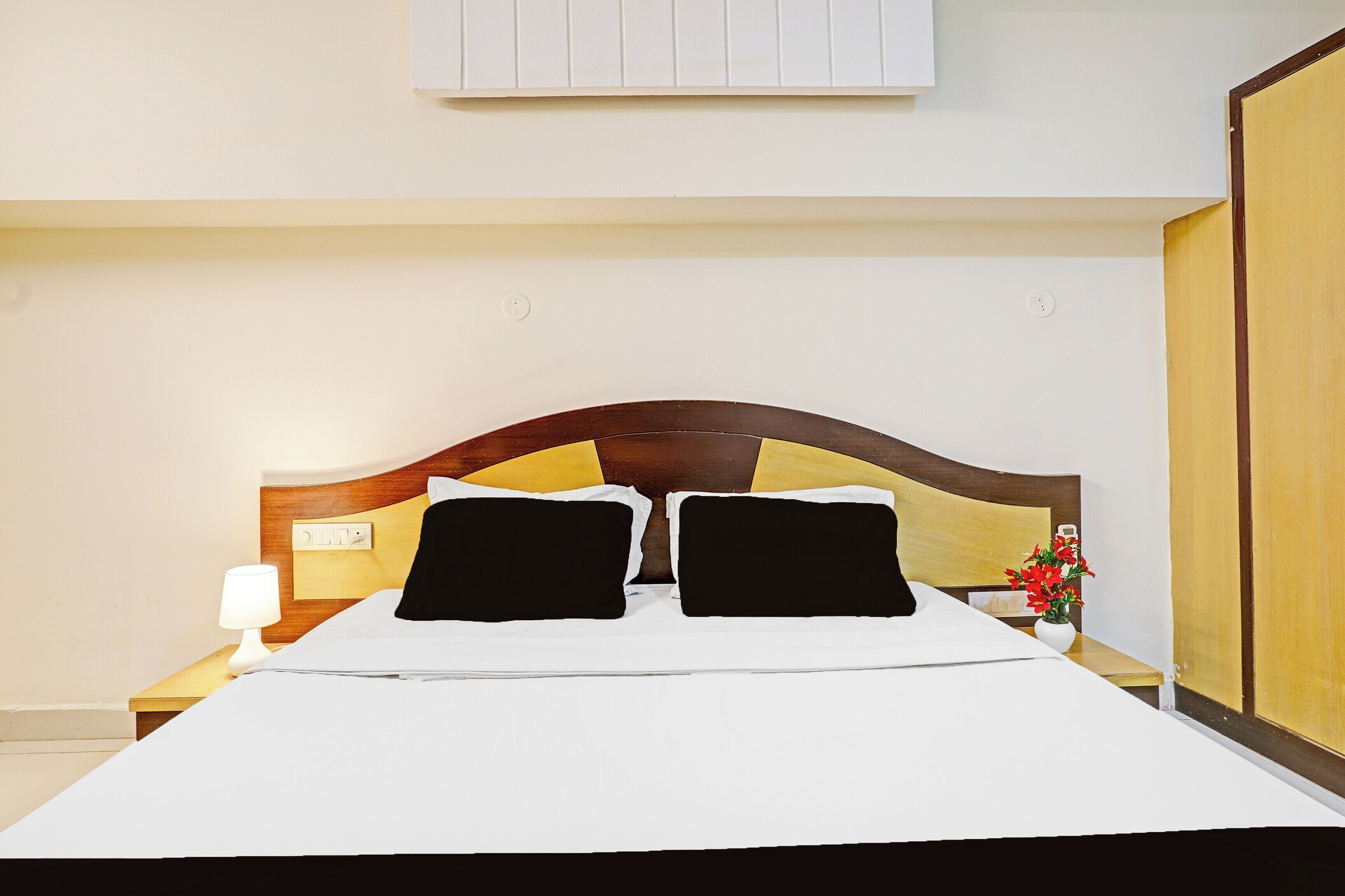 Quarto de hotel com cama, mesas de cabeceira, abajur e luminária na parede.