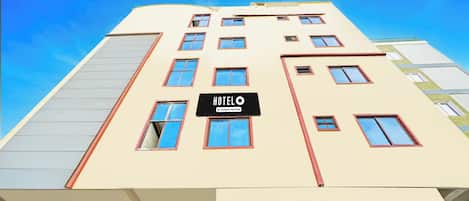 A hotel building with multiple windows and a sign indicating it is company serviced.
