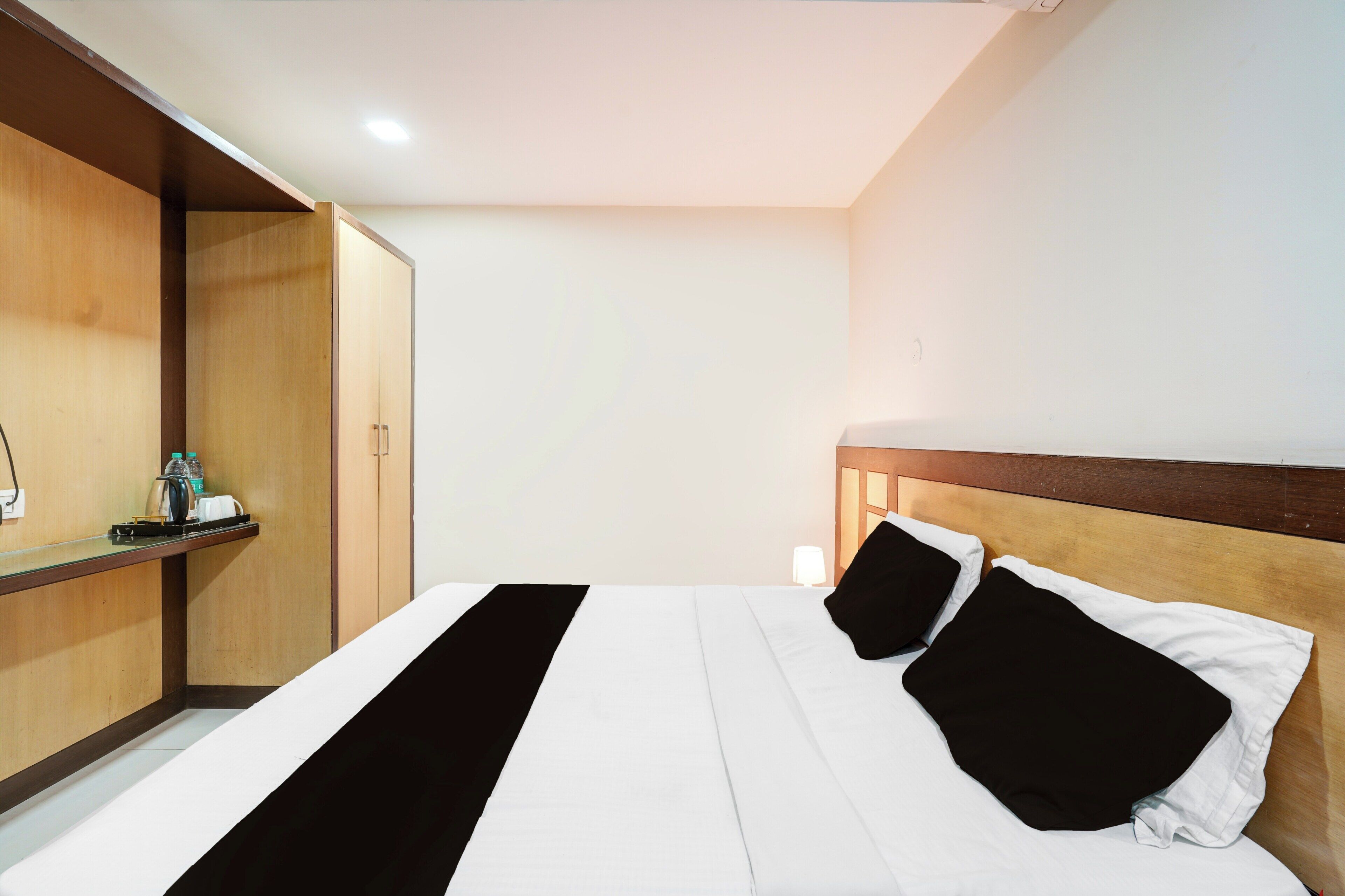 A hotel room with a bed, a wooden headboard, a nightstand, and a wardrobe.