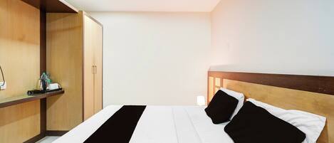 A hotel room with a bed, a wooden headboard, a nightstand, and a wardrobe.