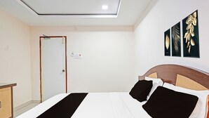 Una habitación de hotel con una cama, cabecera de madera, mesita de noche y una puerta.