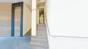 Una escalera que lleva a un cuarto con una puerta cerrada y un ventanal.