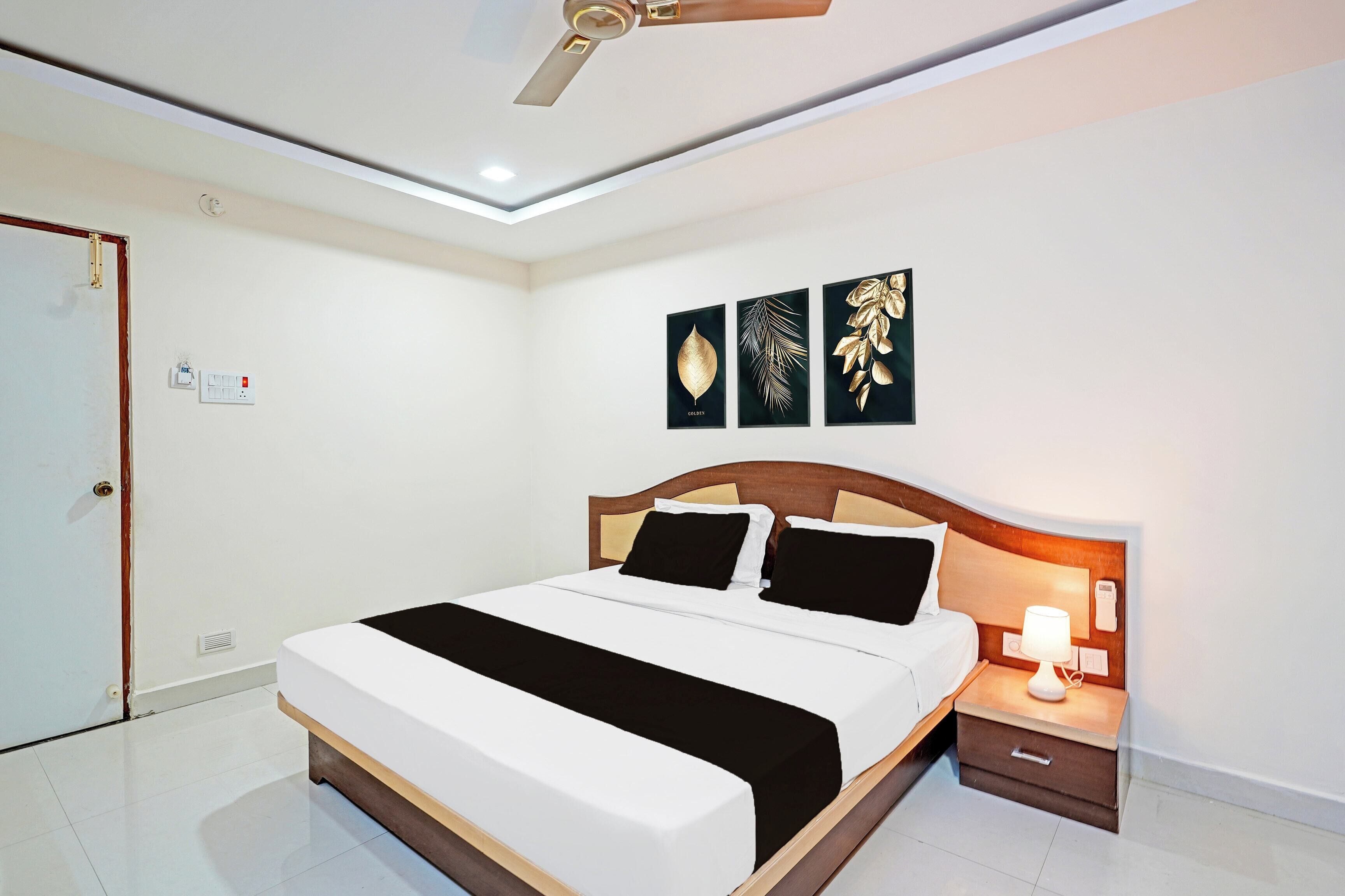 Ein Hotelzimmer mit Bett, Nachttisch, Lampe und Wandbild.