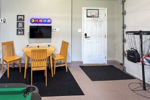 Una habitación con televisión, sillas de madera, aro de baloncesto y una puerta.