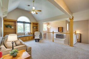 Un vaste salon doté d’un haut plafond, d’un ventilateur de plafond, d’une grande fenêtre, d’une cheminée et d’un escalier avec une rampe.