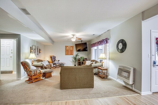 A living room with a sofa, chairs, a coffee table, a fireplace, and a ceiling fan.