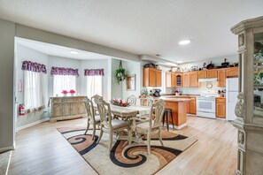 A spacious kitchen with wooden cabinets, a central island, and a dining area with a table and chairs.