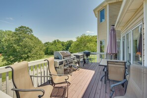 Una terraza con mobiliario exterior, una parrilla y una mesa cubierta con sombrilla.