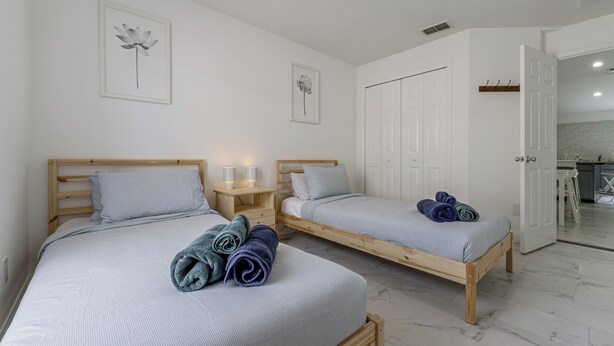 Ein Schlafzimmer mit zwei Einzelbetten, einem Nachttisch aus Holz mit einer Lampe und einem Kleiderschrank.