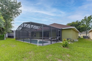 A house with a screened-in porch, a swimming pool, and a green lawn. - Poolside Fun 8 Mi to Disney! Family Getaway (Kissimmee)