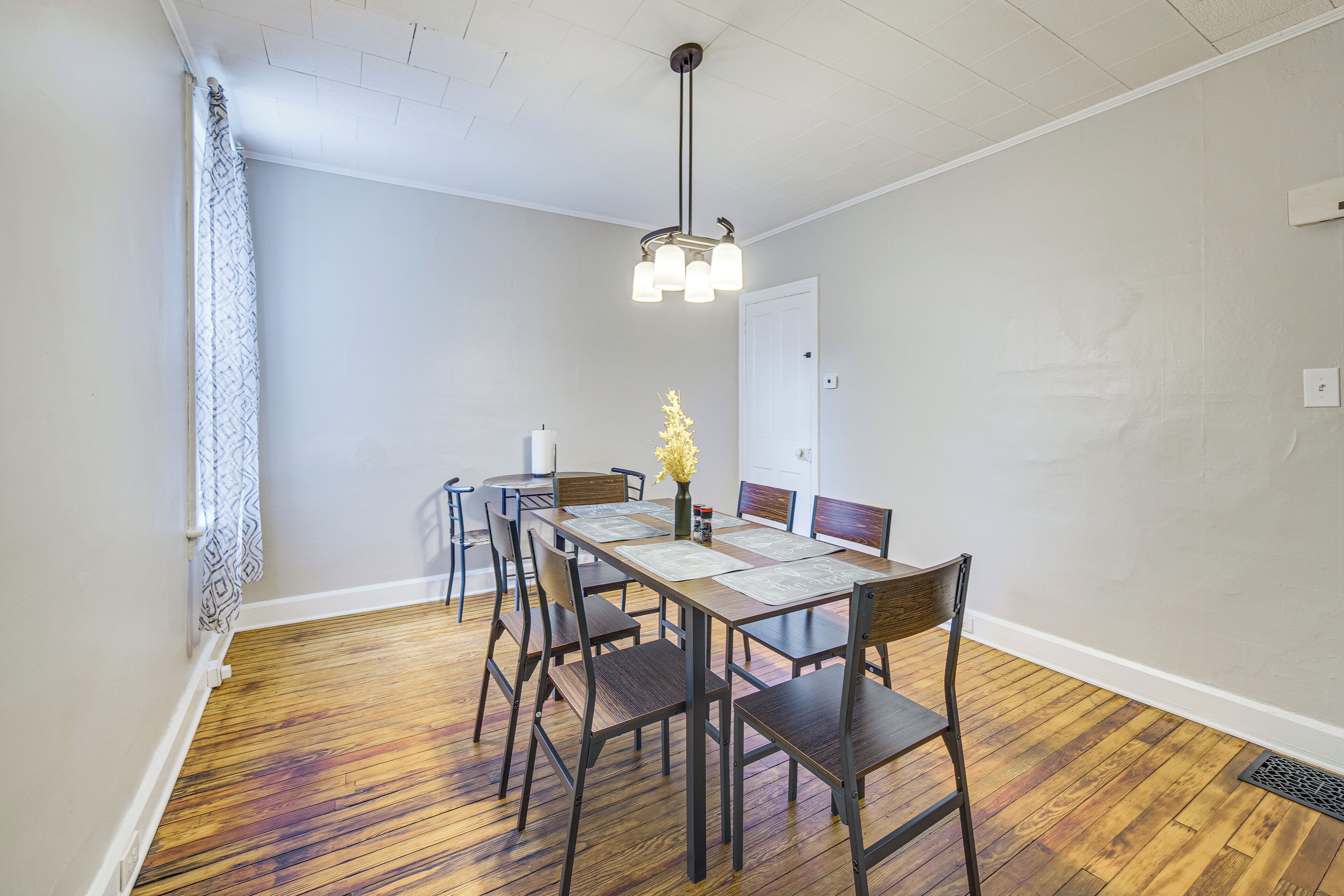 A dining area with a wooden table, chairs, and a hanging light fixture.