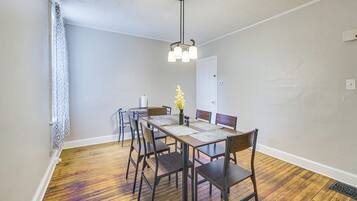 A dining area with a wooden table, chairs, and a hanging light fixture.