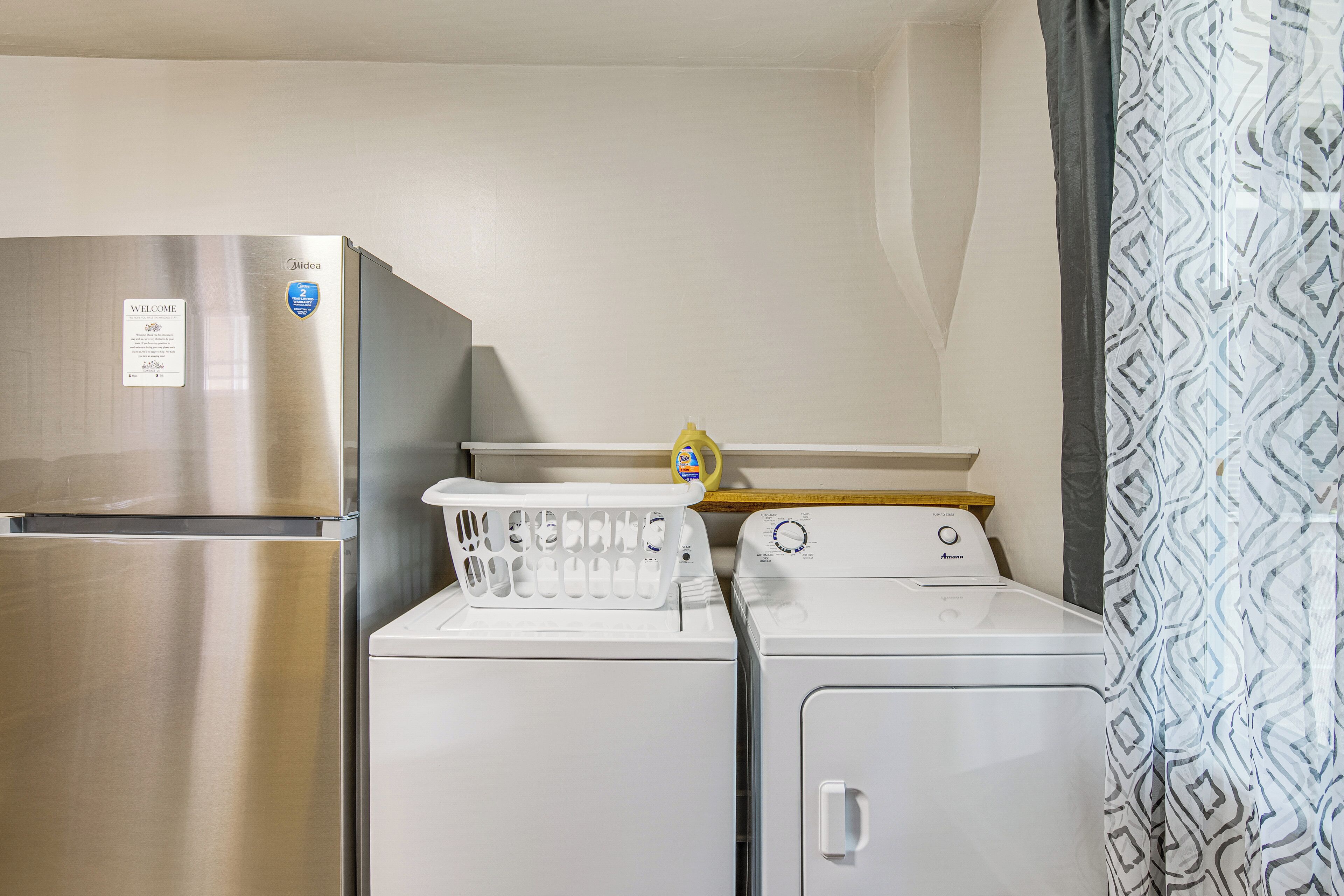 Une cuisine compacte équipée d’un réfrigérateur en acier inoxydable, d’un lave-linge et d’un sèche-linge.