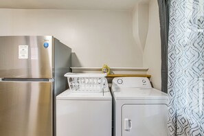 Cuina compacta amb nevera d'acer inoxidable, rentadora i assecadora.
