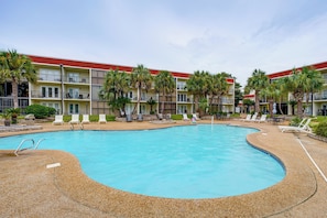 A hotel with a swimming pool surrounded by lounge chairs and palm trees. - Walk to Beach! Biloxi Condo w/ Community Perks (Biloxi)