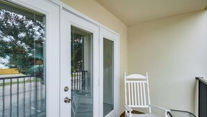 A white chair and a table on a balcony with a white door and window blinds. - Walk to Beach! Biloxi Condo w/ Community Perks (Biloxi)