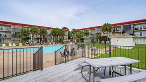 A hotel with a swimming pool, outdoor seating, and a fenced patio area. - Walk to Beach! Biloxi Condo w/ Community Perks (Biloxi)
