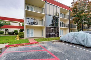 Ein mehrstöckiges Gebäude mit Balkonen, einem überdachten Parkbereich und einem Hydranten.