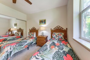 A room with two beds, each with a floral bedspread, a bedside table with a lamp, a mirror, and a picture frame on the wall. - Halii Kai Condo Close in Proximity to Ocean/Pool (Waikoloa Village)