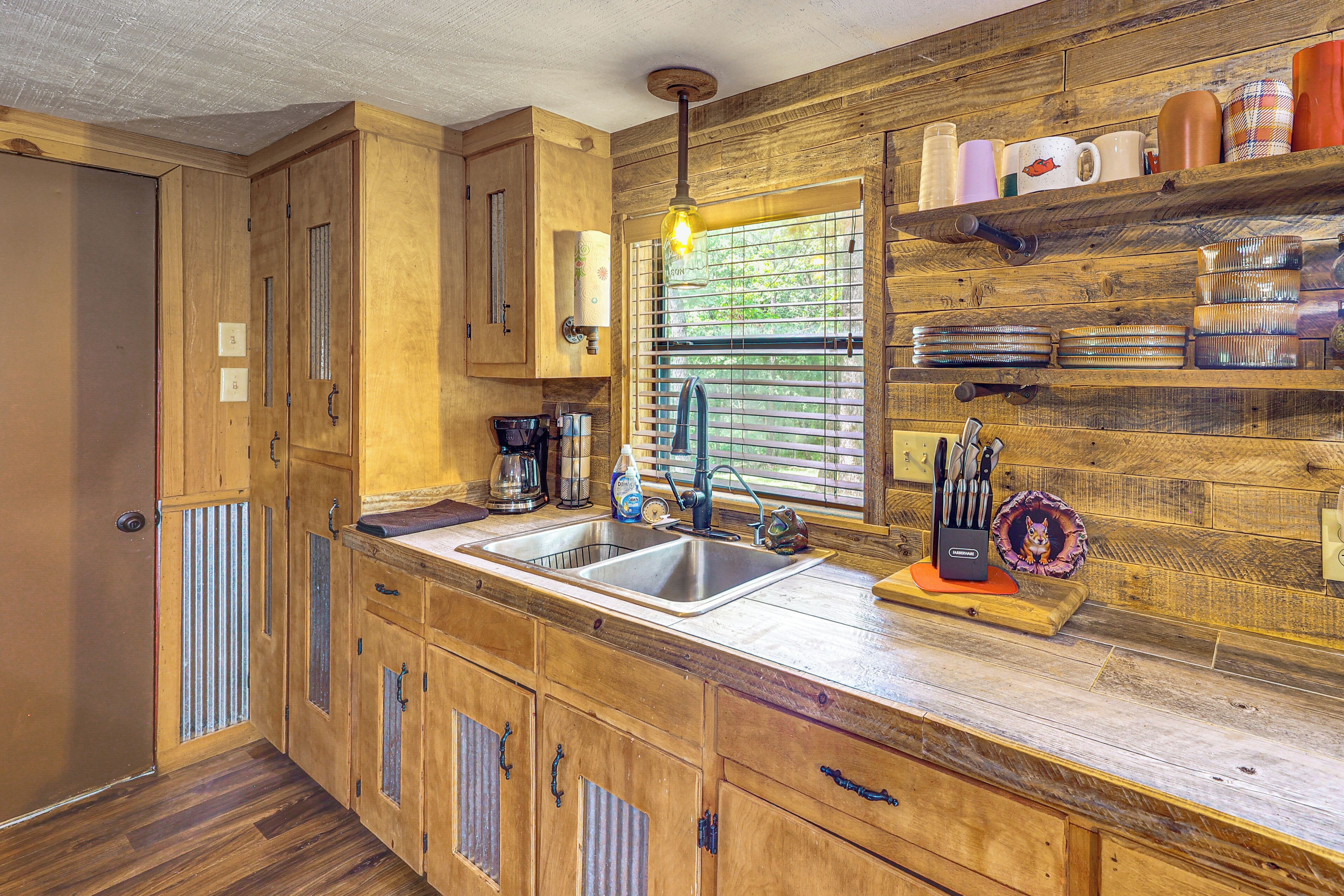 A kitchen with wooden cabinets, a double sink, and a window with blinds.