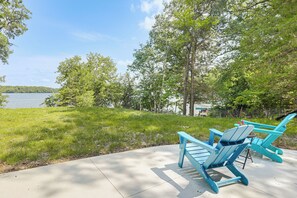 Eine Terrasse am See mit zwei blauen Adirondack-Stühlen und einer Betonplattform.