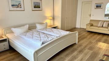 A bedroom with a bed, bedside tables, a wardrobe, a sofa, and a lamp.