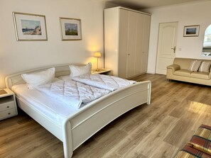 Ein Schlafzimmer mit Bett, Nachttischen, einem Kleiderschrank, einer Couch und einer Lampe.