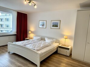 Et hotelværelse med seng, sengeborde, et klædeskab og et vindue med gardiner.