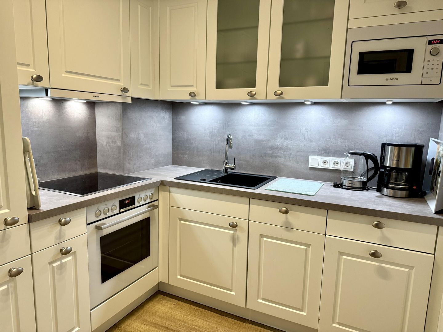 A modern kitchen with white cabinetry, a built-in microwave, a stove, and a coffee maker.