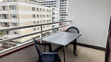 Un balcon avec une table et des chaises, donnant sur un paysage urbain composé de nombreux bâtiments.