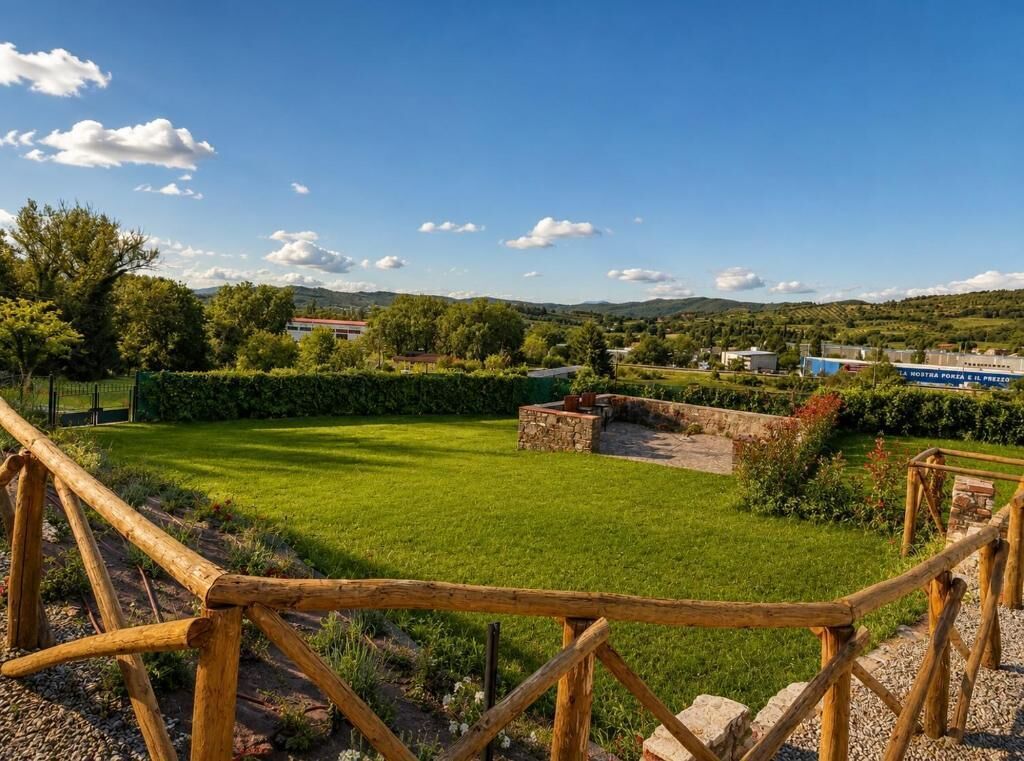 Ein gepflegter Garten mit Steinbauwerk, Holzzaun und freiem Blick auf die umliegende Landschaft.