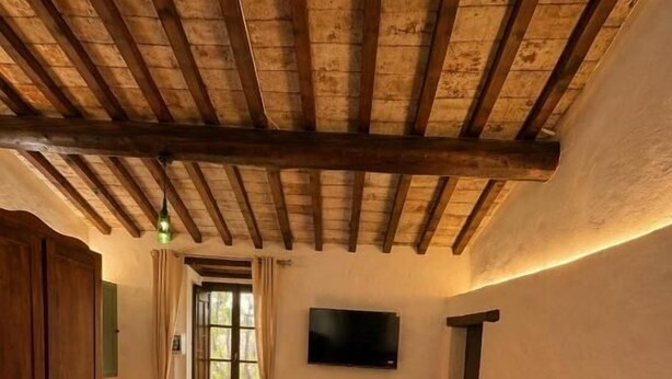 Una habitación con techo de madera, sofá de cuero marrón, mesa de madera y televisor montado en la pared.