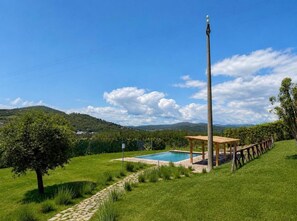 A swimming pool with a wooden deck and a gazebo, surrounded by a grassy area and trees, with hills in the background. - Tenuta Valmarino - Adults only (Corciano)