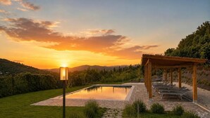Un entorno tranquilo al aire libre con piscina, una pérgola de madera y un camino de piedra.