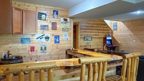 A wooden interior with a bar area, wooden cabinets, and various signs on the walls. - Adventure Bay | Dock, Kayaks, Firepit & Game Room (Friendship)