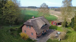 Een rieten huis met een verharde oprit en een kleine tuin.