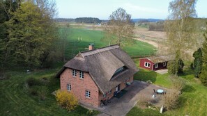 Ein Haus mit Strohdach, einer gepflasterten Auffahrt und einem kleinen Garten.