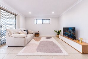 Una sala de estar moderna con un sofá, un televisor, una planta y una alfombra decorativa.