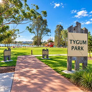 A park entrance with a sign reading 'TYGUM PARK' and a pathway leading into the park.