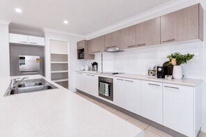 A modern kitchen with white cabinetry, stainless steel appliances, and a central island.