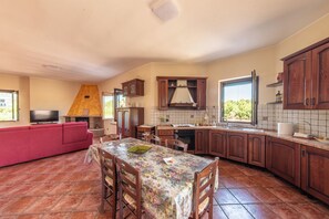 A spacious kitchen with a dining area, a fireplace, and a large window. - Casa Clementina - Alle porte di S. Agata dei Goti (Giardoni)