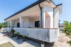 A covered outdoor area with a concrete floor, potted plants, and a staircase leading to an upper level. - Casa Clementina - Alle porte di S. Agata dei Goti (Giardoni)