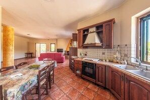 A spacious kitchen with a dining area, a red sofa, and a staircase leading to another level. - Casa Clementina - Alle porte di S. Agata dei Goti (Giardoni)